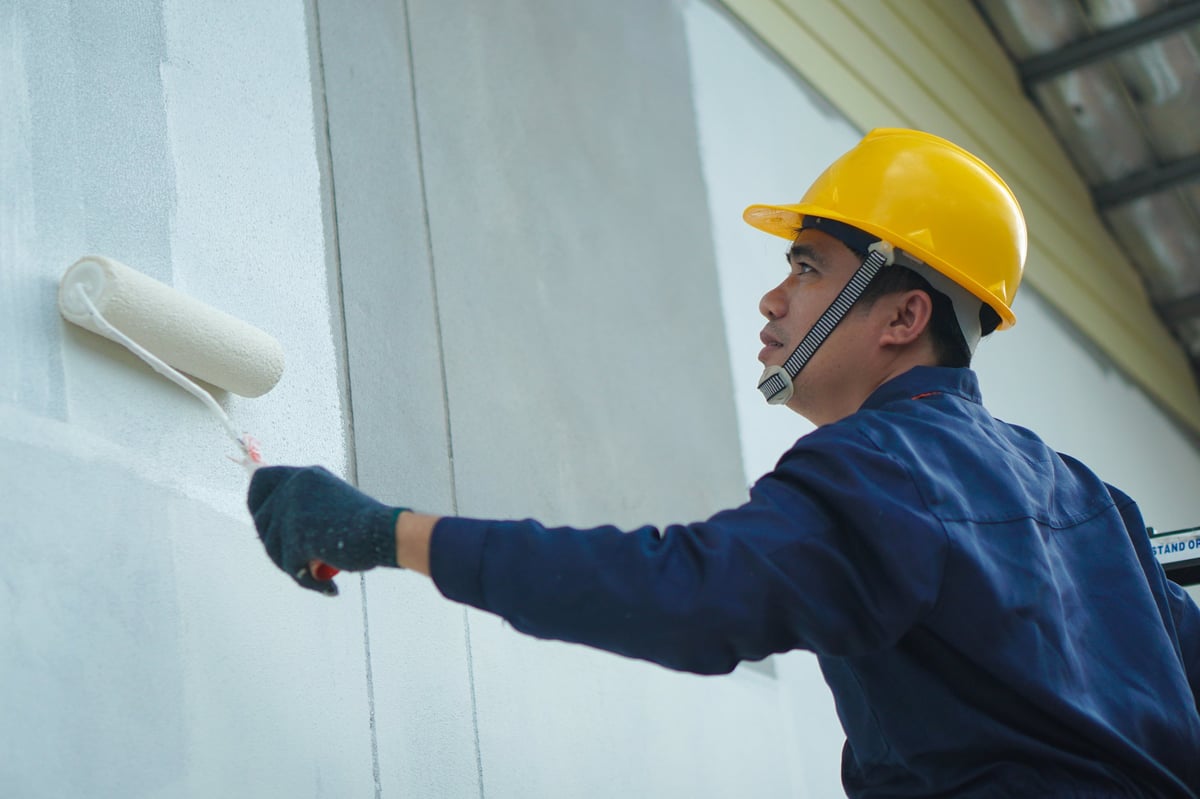 Professional painter applying fresh coat of paint to interior wall in modern home
